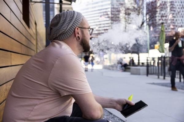 A man vapes along the Chicago Riverwalk on April 12, 2023. 