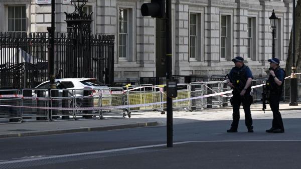 Police officers stand near the car that was driven into the gates of 10 Downing Street.