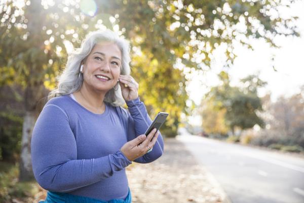 A senior woman putting in earbuds while getting ready to take a walk