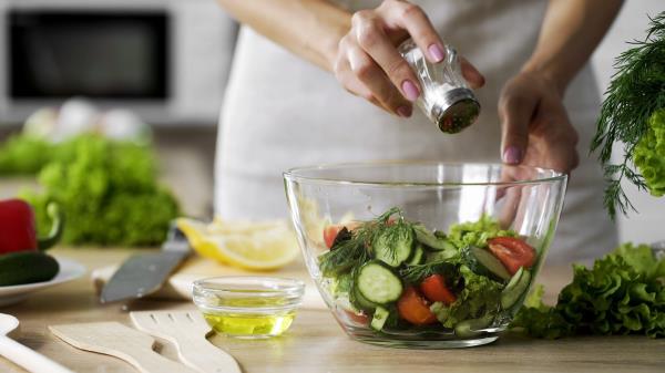 Woman putting salt on salad