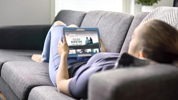 Woman choosing movie from o<em></em>nline stream service with tablet. Watching series with on demand video (VOD) website concept. Streaming digital film from site by tv network. Mockup on smart device screen.